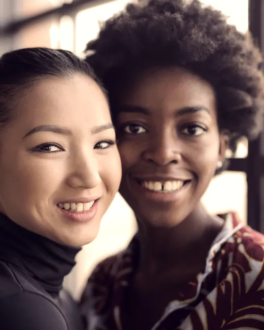 Two friends standing close together, smiling.